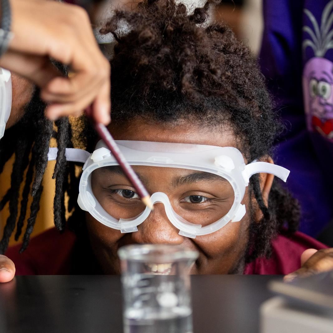  A student looks at a beaker with goggles on